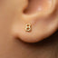 A close-up of a person's ear with a small gold earring featuring the number 8.