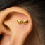 A close-up of a person's ear with a gold earring featuring a spiral design.