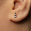 A close-up of a person's ear with a small silver earring in the earlobe.