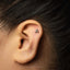 A close-up of a person's ear with a small letter "A" stud in the earlobe.