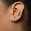 A close-up of a person's ear with a small silver earring in the earlobe.