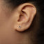A close-up of a person's ear with a small silver hexagonal earring in the earlobe.