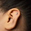 A close-up of a person's ear with a small silver earring in the earlobe.