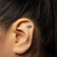 A close-up of a person's ear with a small silver earring in the earlobe.
