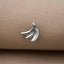 A silver-colored pendant in the shape of a banana is resting on a beige fabric surface.