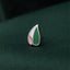 A silver pin with a green and pink leaf design rests on a dark green fabric.