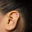 A close-up of a person's ear with a small, colorful earring in the earlobe.