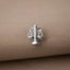 A silver-colored charm in the shape of a scale, which is a symbol often associated with justice and fairness.