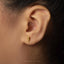A close-up of a person's ear with a small gold earring in the earlobe.