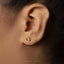 A close-up of a person's ear with a small gold earring in the earlobe.