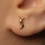 A close-up of a person's ear wearing a small gold earring with a small, intricate design.