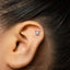 A small silver earring with a menorah design is visible in the image.