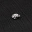 A small, silver, metal frog-shaped object is resting on a textured black surface.
