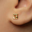 A close-up view of a person's ear wearing a small gold-colored earring.