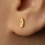 A close-up of a person's ear with a small gold earring in the earlobe.