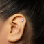 A close-up of a person's ear with a small silver earring in the earlobe.