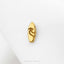 A single gold-colored pin or badge with a wave design on it, resting on a white surface.