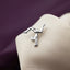 A silver pin in the shape of a hand doing a handstand on a fabric surface.