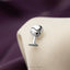 A silver wine glass-shaped cufflink is attached to a beige fabric surface.