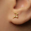 A close-up of a person's ear with a small gold-colored earring featuring a deer design.