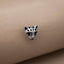 A silver-colored metal charm in the shape of a cat's head is resting on a beige fabric surface.