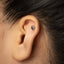 A close-up of a person's ear with a small silver earring in the earlobe.
