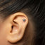 A silver earring with a small cat-like design is visible in the person's ear.