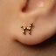 A close-up of a person's ear with a small gold earring shaped like a dog.