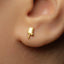 A close-up of a person's ear with a small gold earring in the earlobe.