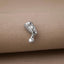A silver-colored metal object, resembling a small statue or figurine, is resting on a beige fabric surface.