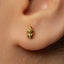 A close-up of a person's ear with a small gold-colored earring in the earlobe.