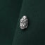 A silver-colored Buddha head pin is attached to a dark green fabric.