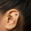 A close-up of a person's ear with a small silver earring in the earlobe.