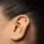 A close-up of a person's ear with a small silver earring in the earlobe.