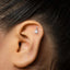 A close-up of a person's ear with a small silver earring in the earlobe.