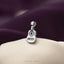 A silver guitar charm is displayed on a white fabric surface against a purple background.