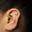 A close-up of a person's ear with a small silver earring in the earlobe.