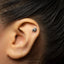A close-up of a person's ear with a small silver earring in the earlobe.