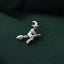 A small silver pin or brooch in the shape of a witch on a fabric surface.