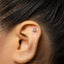 A close-up of a person's ear with a small silver earring in the earlobe.