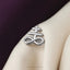 A silver infinity symbol pin is displayed on a white fabric surface.