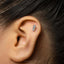A silver earring with a small embossed design is visible in the person's ear.