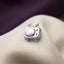A small silver TV-shaped pendant or charm is displayed on a white fabric surface.