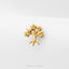 A gold-colored tree-shaped earring is displayed against a white background.
