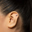 A close-up view of a person's ear with a small silver earring in the earlobe.