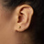 A close-up of a person's ear with a small gold earring in the earlobe.