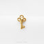 A gold-colored key-shaped pendant with a skull design, placed on a white background.