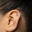A close-up of a person's ear with a small silver earring in the earlobe.