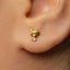 A close-up view of a person's ear adorned with a small gold earring featuring a small bird-like design.