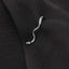 A silver snake-shaped earring is resting on a dark fabric.